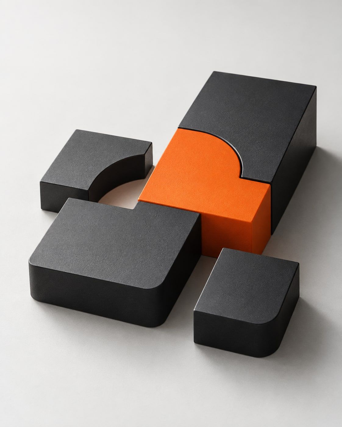 Matte graphite blocks with curved edges fitted around a single orange block.