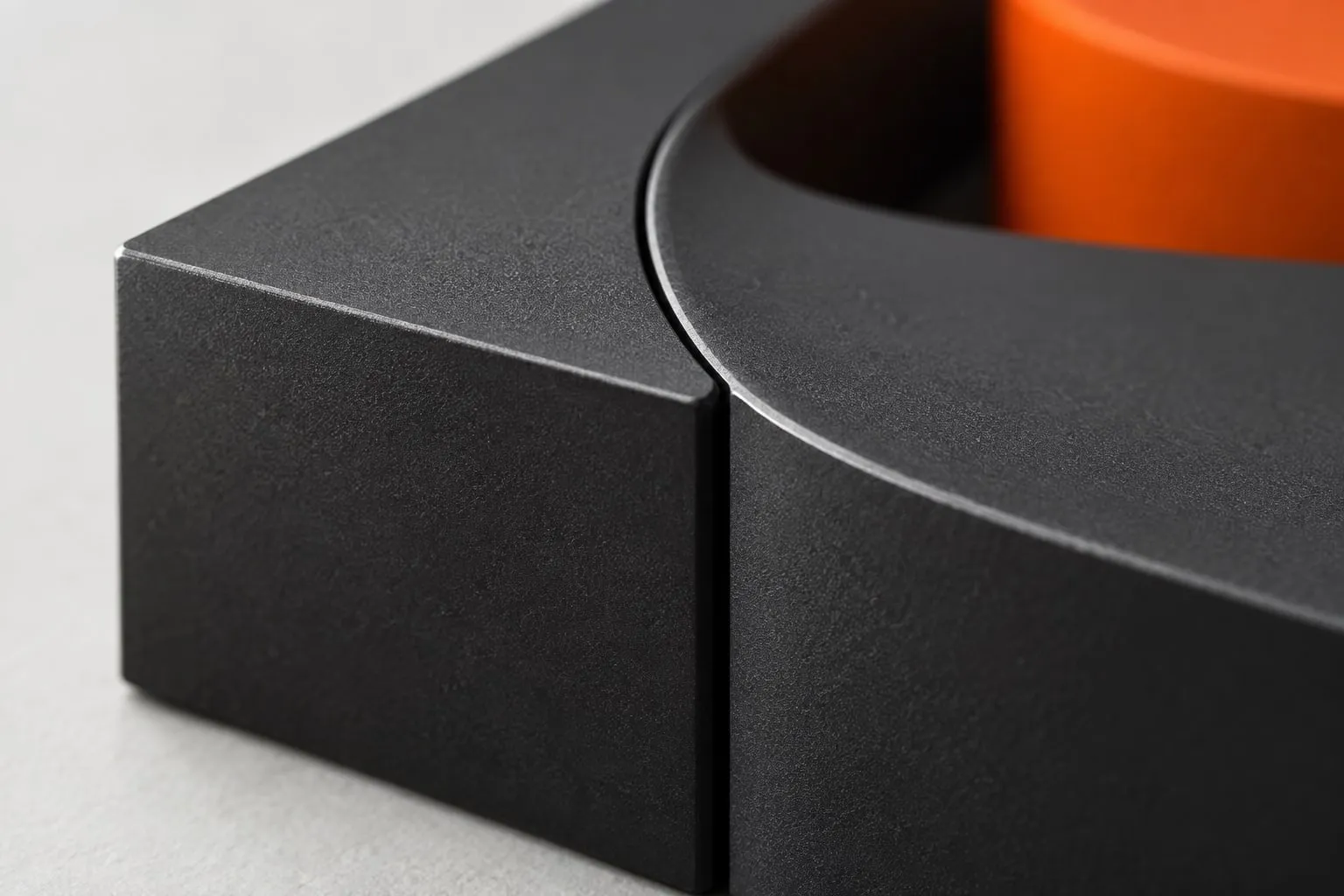 Close-up of two graphite blocks meeting along a precise curved seam, with an orange block behind.